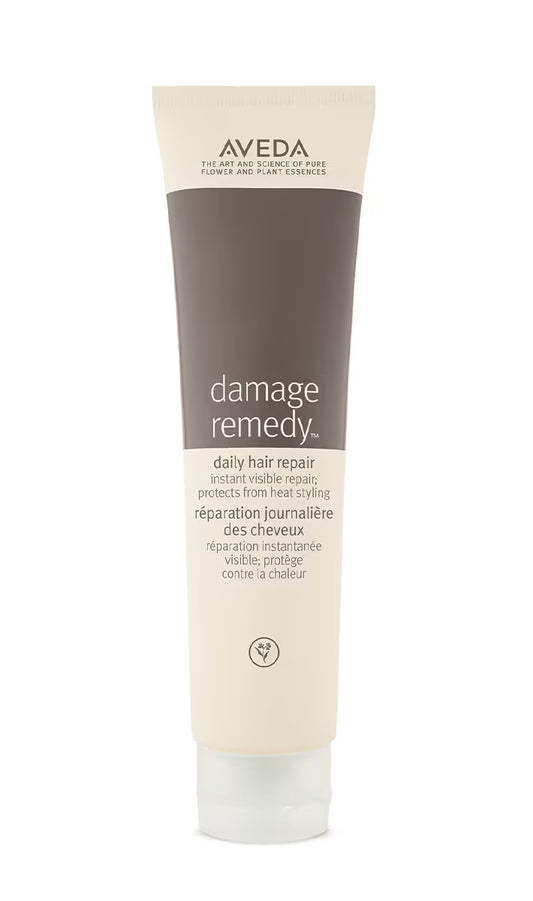 A tube of Aveda Damage Remedy daily hair repair hair care product, featuring a dark brown and cream color scheme on a white background.